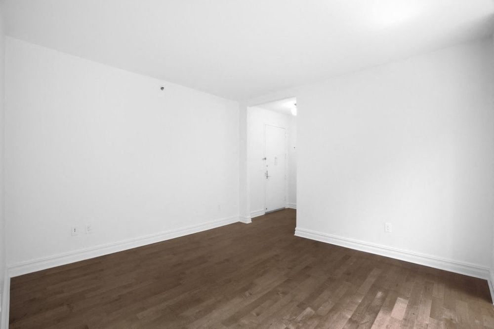 an empty living room with white walls and wood floors