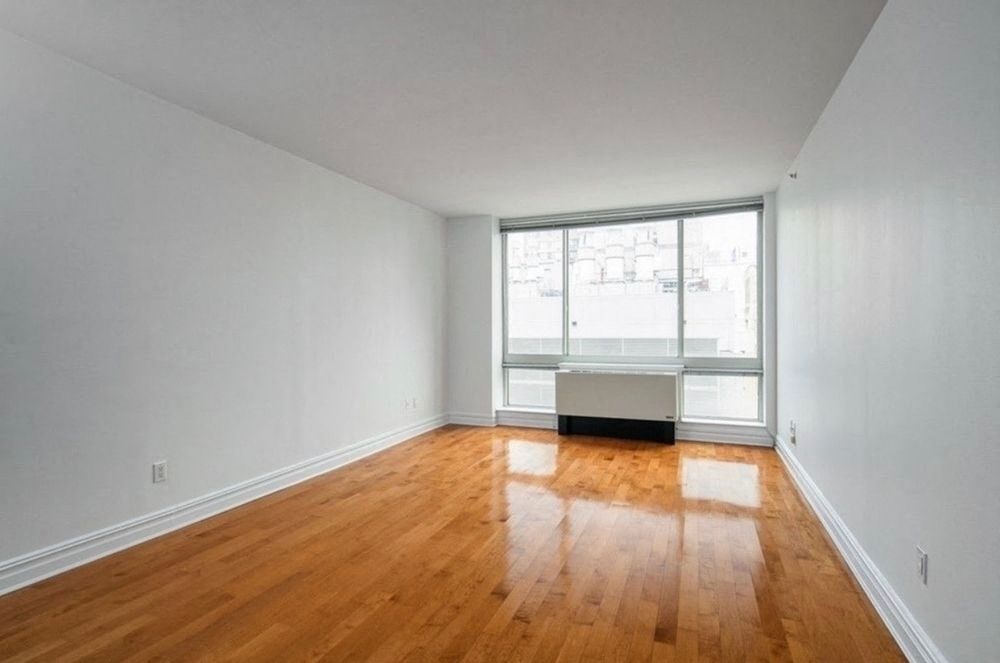 an empty living room with a window and wooden floors