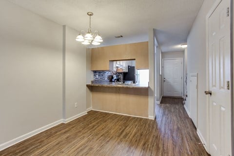 an empty living room and kitchen with a hard wood floor