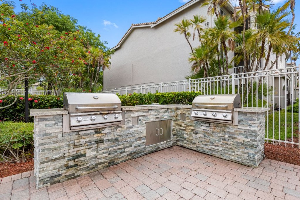 two barbecue grills on a stone wall in front of a house
