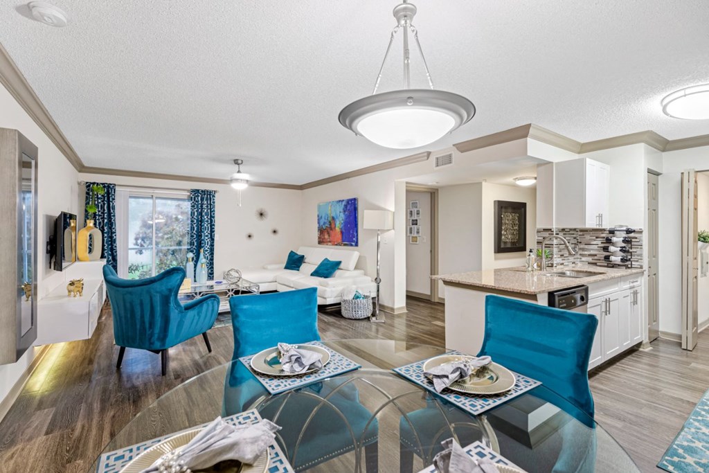 a living room and kitchen with a glass table and chairs