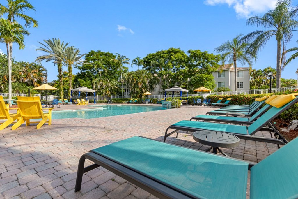 a resort style swimming pool with yellow and blue deck chairs