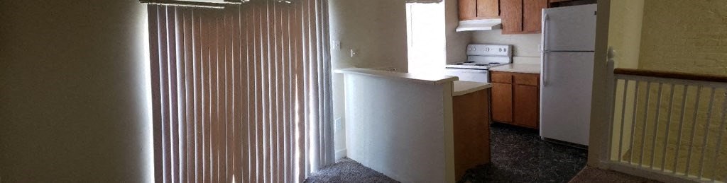 an empty kitchen with a refrigerator and a door