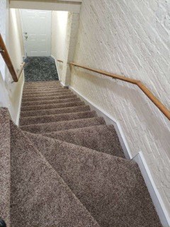 a carpeted stairway with a railing and carpeted stairs