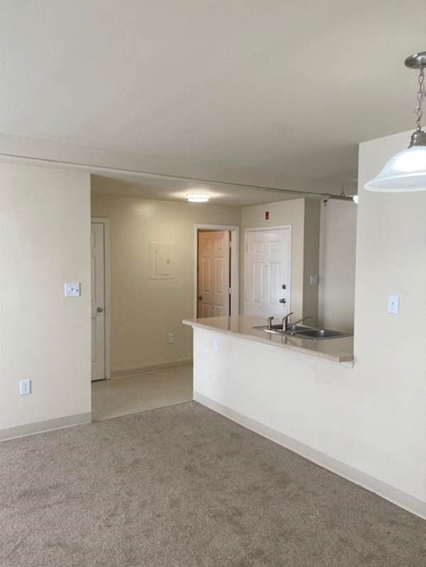 an empty living room and a kitchen with a sink