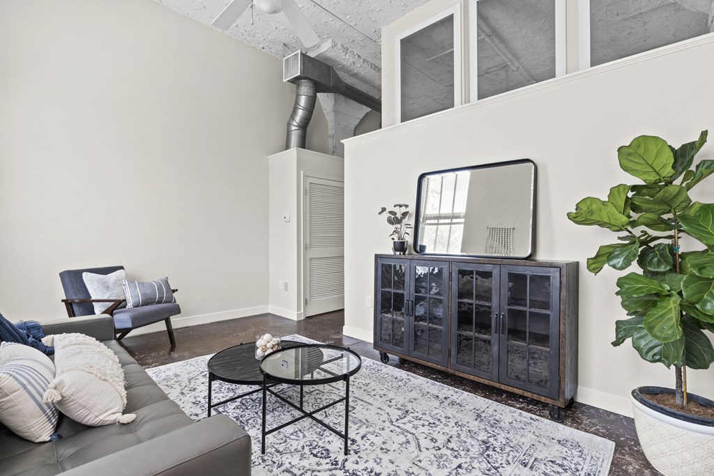 a living room with a couch and a chair and a mirror