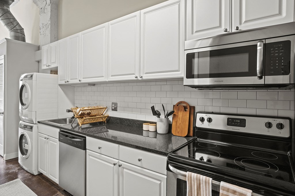 a kitchen with white cabinets and black appliances