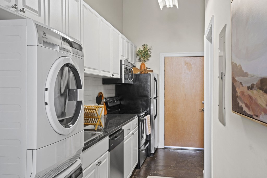 a kitchen with white cabinets and a washing machine and a refrigerator