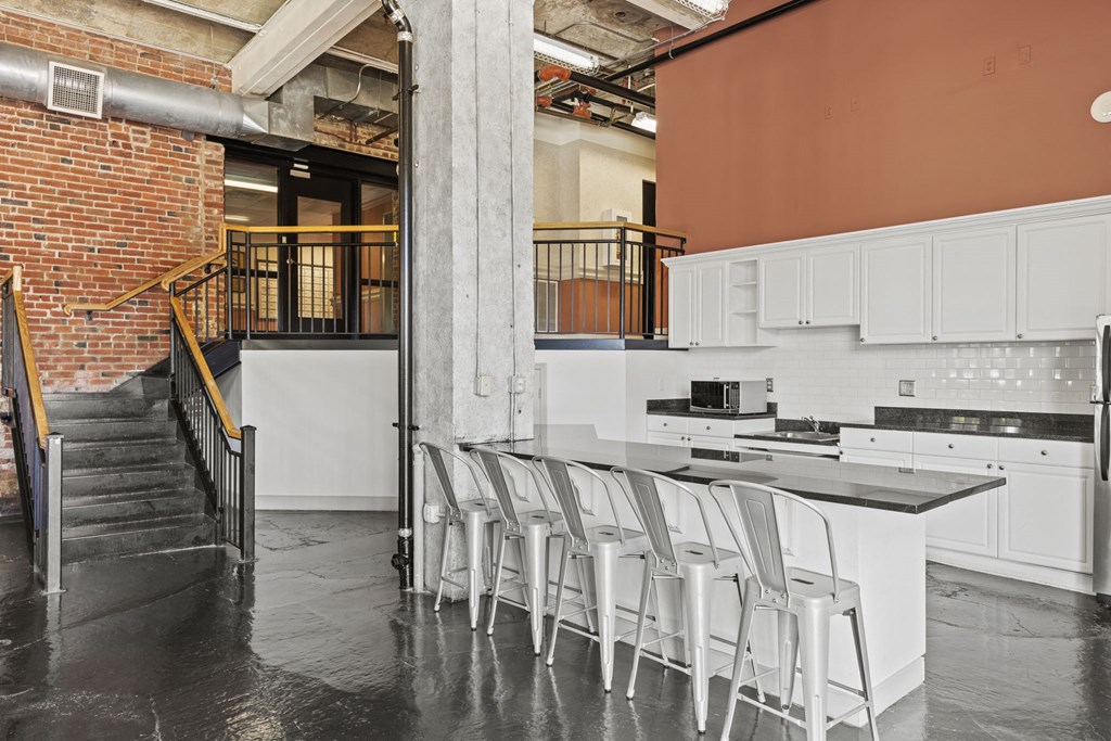 a kitchen with white cabinets and bar stools next to a staircase