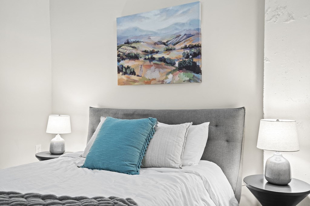 a bedroom with a bed and a painting on the wall