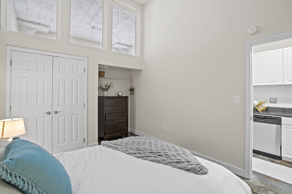 a bedroom with a bed and a door to a kitchen