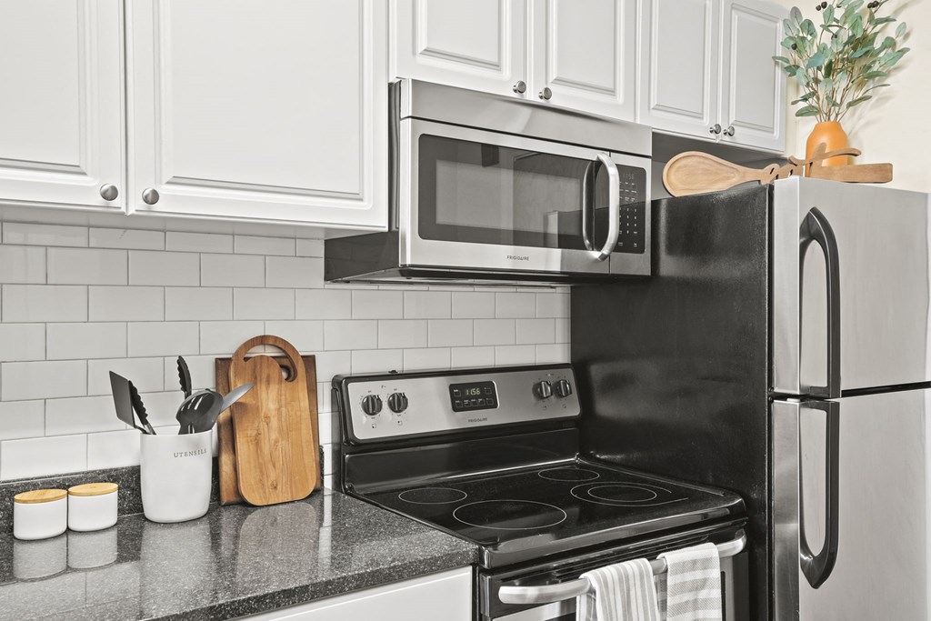a kitchen with white cabinets and a black stove and microwave