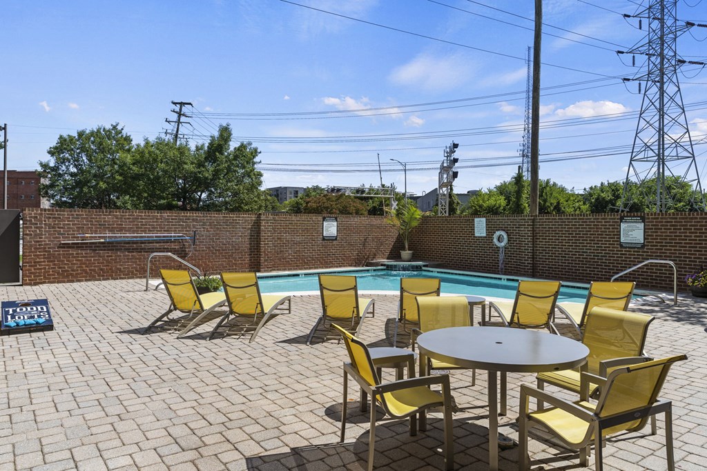 a pool with yellow chairs and a table and chairs around it