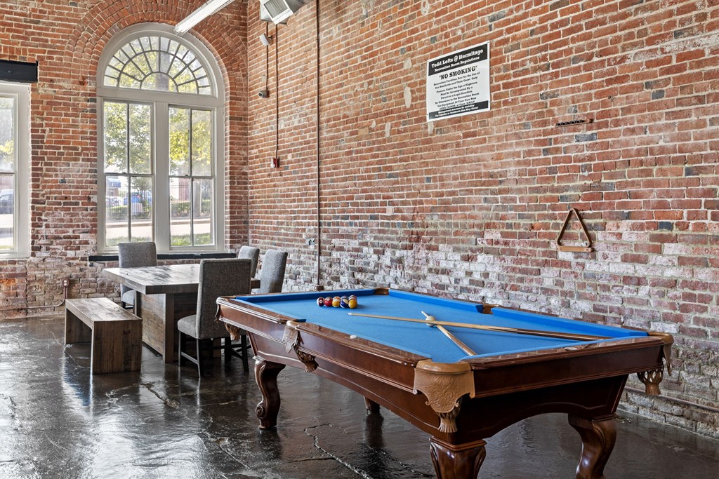 a pool table in a room with a brick wall
