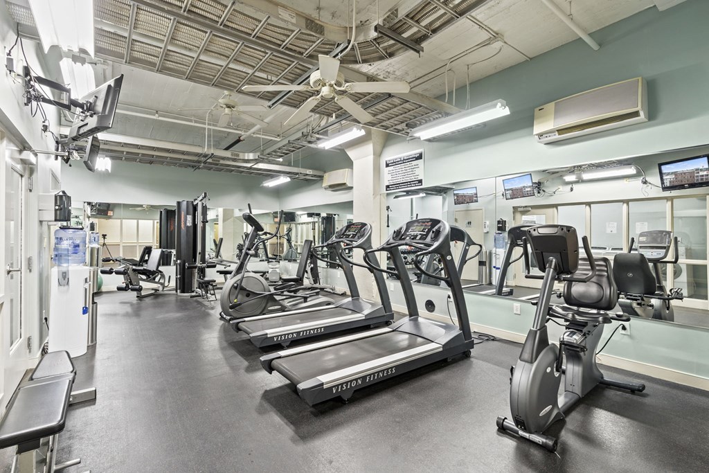 a gym with cardio equipment and a ceiling fan