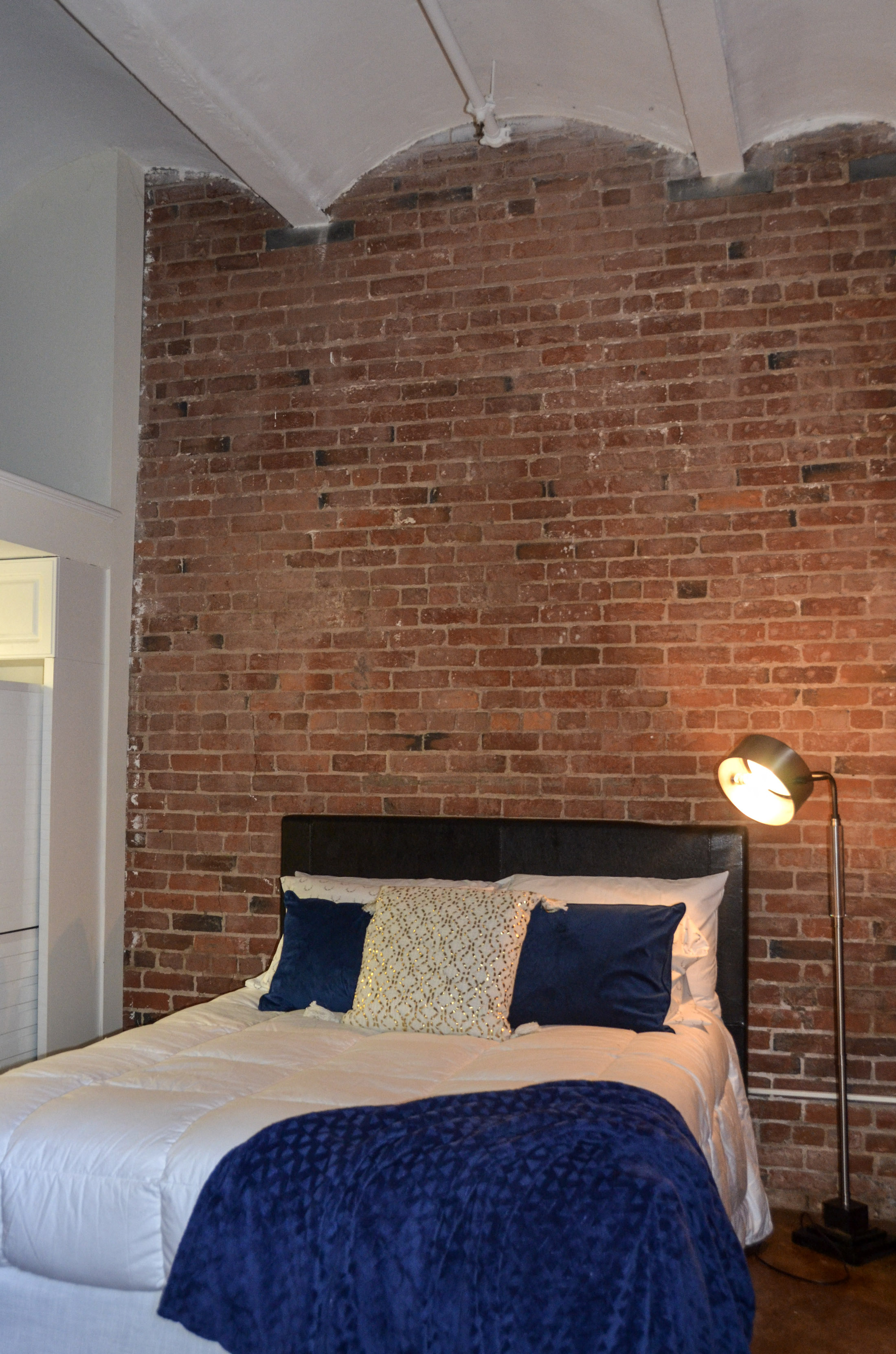 a brick wall in a bedroom with a bed