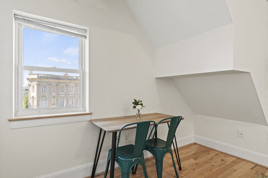 a dining room with a window and a table with three chairs