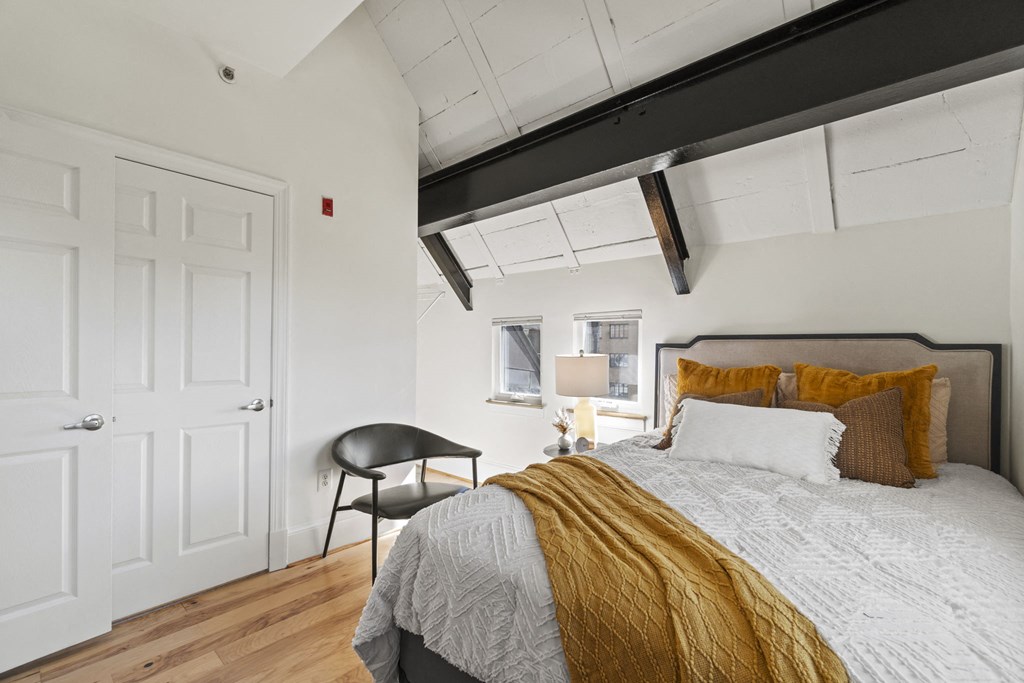 a bedroom with a bed and a chair and a window