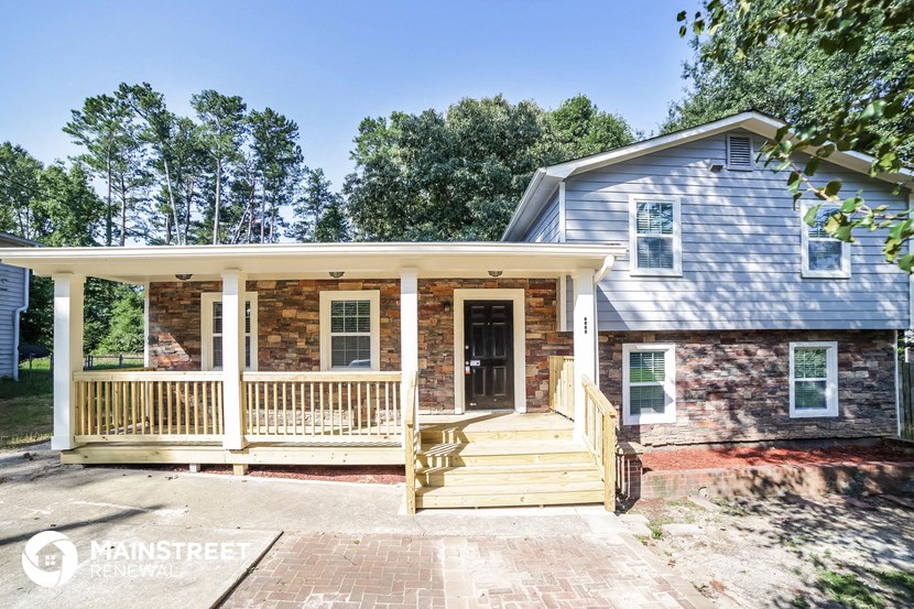 a brick house with a porch and a blue roof