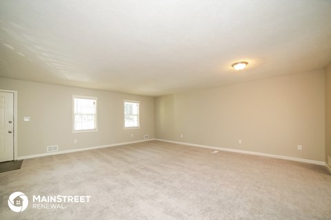 the spacious living room with white carpet and white walls