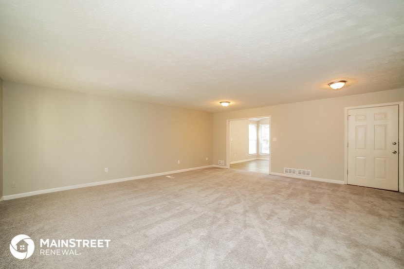 the spacious living room with carpeting and a white door