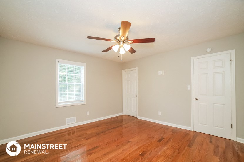 the living room of a house with a ceiling fan and wood floors