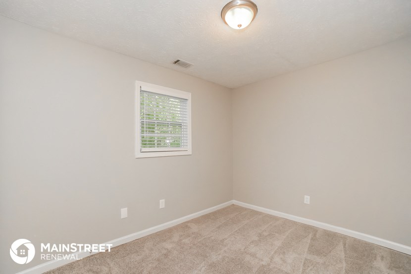 the upstairs bedroom with carpeted flooring and a window