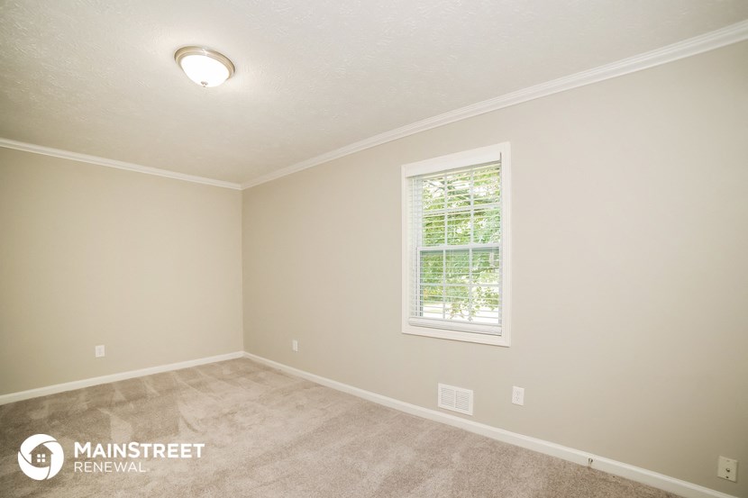 the upstairs bedroom with carpeting and a window