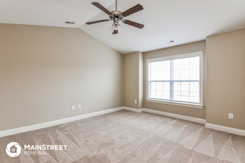 an empty room with a ceiling fan and a window