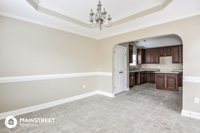 a kitchen with brown cabinets and a white door and a chandelier