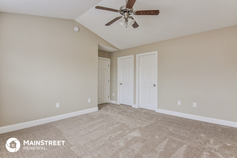 the spacious living room with carpeting and a ceiling fan