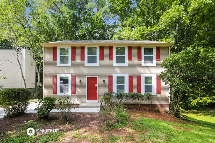 a house with red shutters and a lawn and trees