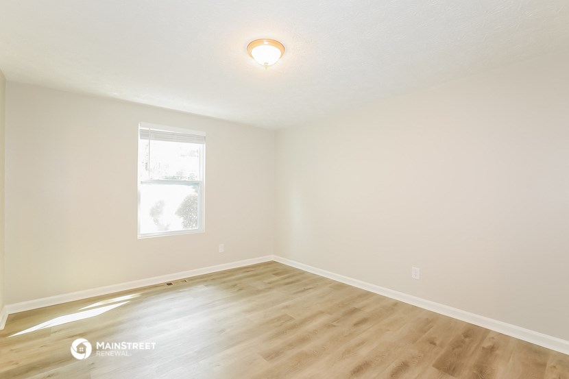 the spacious living room with wood flooring and a window