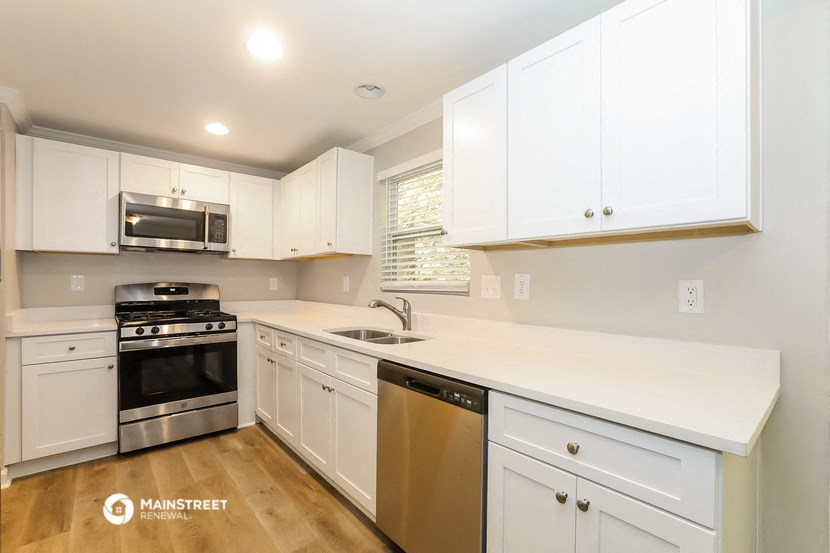 an updated kitchen with white cabinets and stainless steel appliances