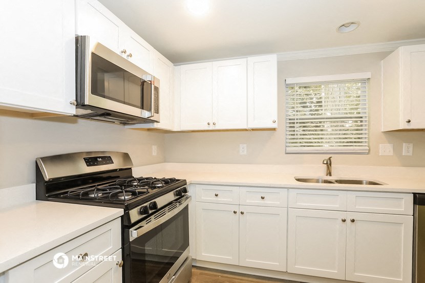 a kitchen with white cabinets and a stove and a microwave