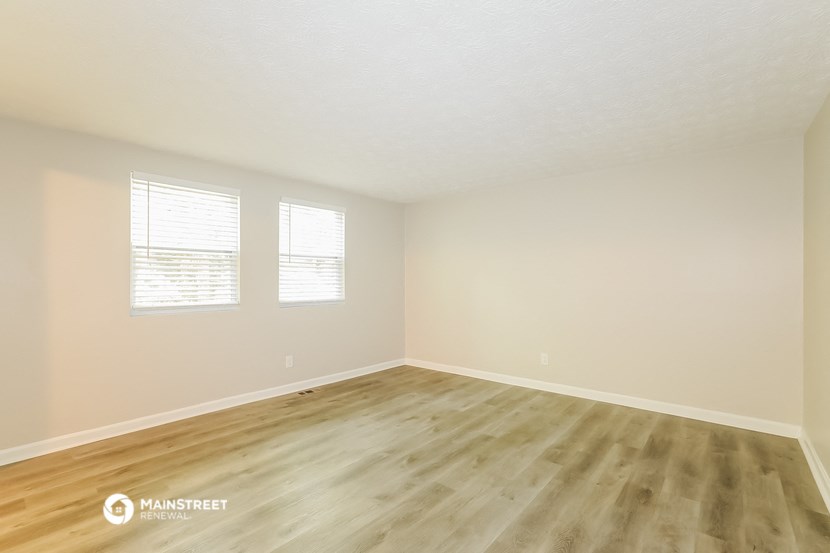 the spacious living room with hardwood floors and white walls
