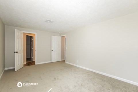 a spacious living room with carpet and white walls