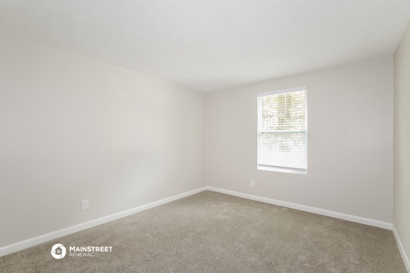 a bedroom with white walls and a window