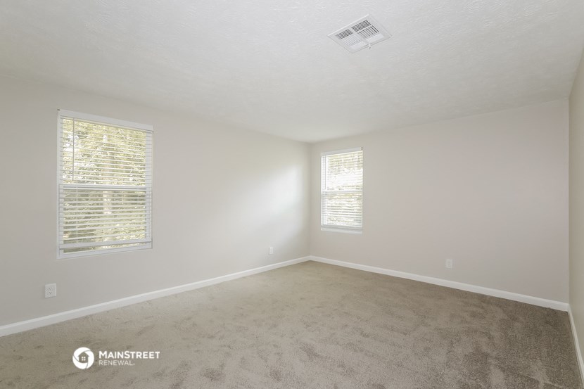 a bedroom with a carpeted floor and two windows