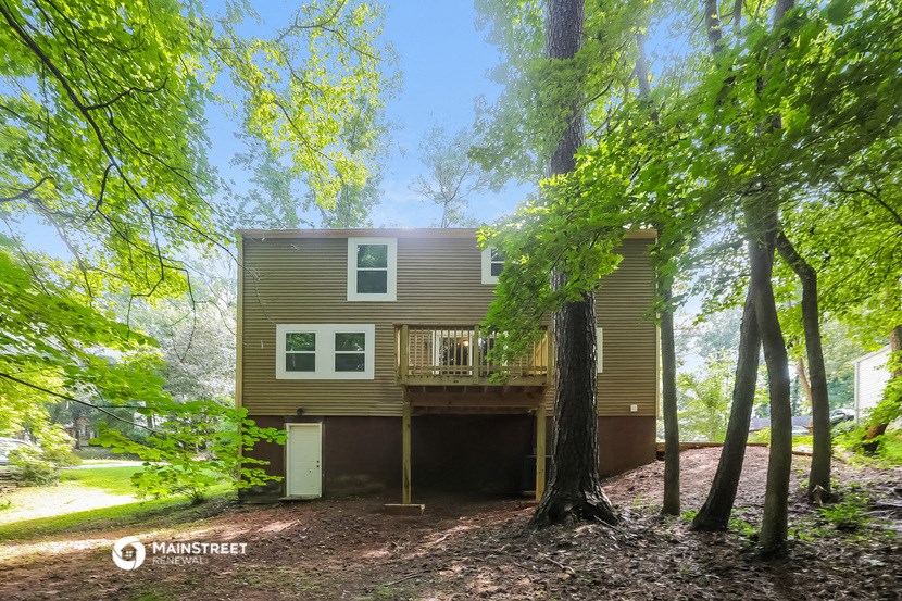 the back of a house in the woods with trees