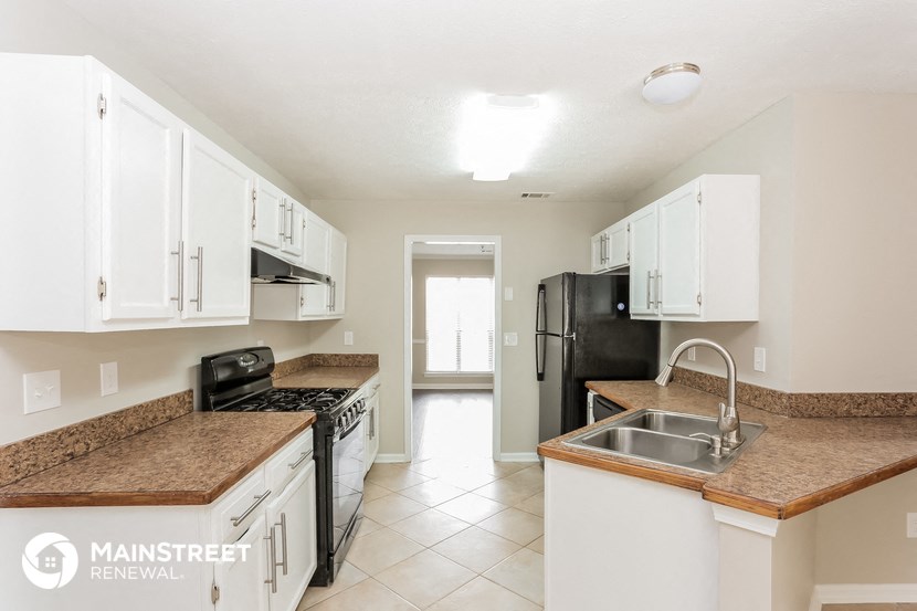 a kitchen with white cabinets and granite counter tops and a black refrigerator