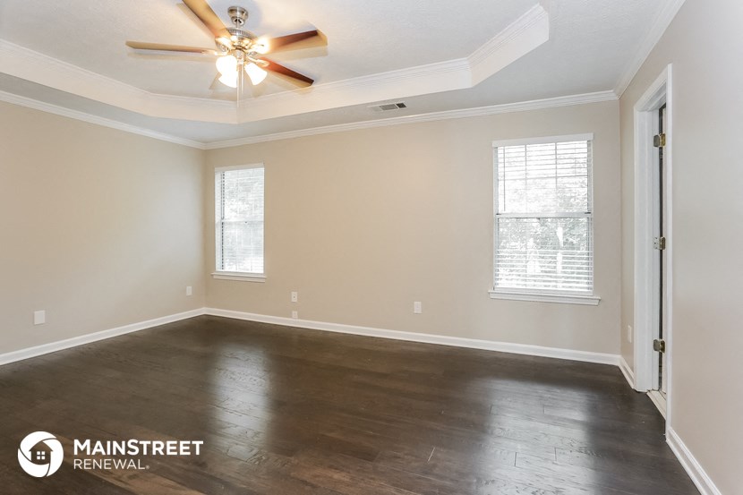 the spacious living room with wood floors and a ceiling fan