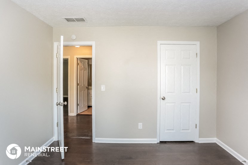 a living room with a white door and a hallway to a closet