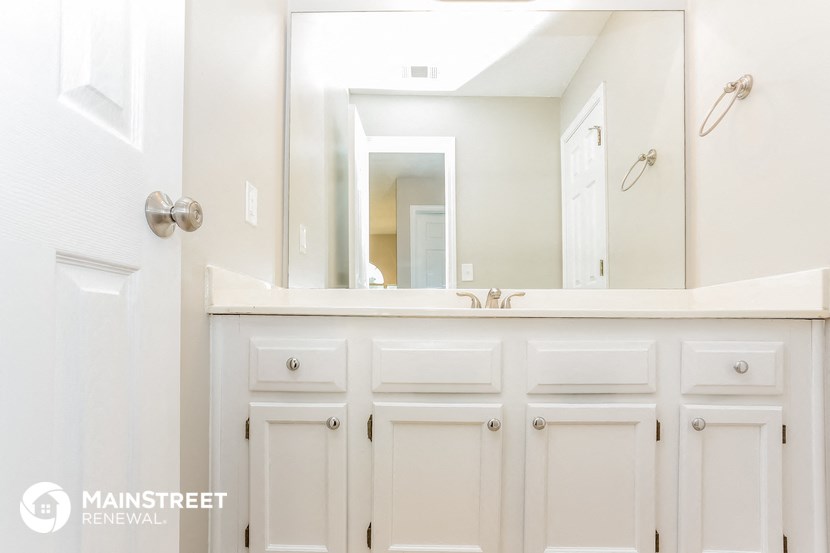 a bathroom with white cabinets and a sink and a mirror