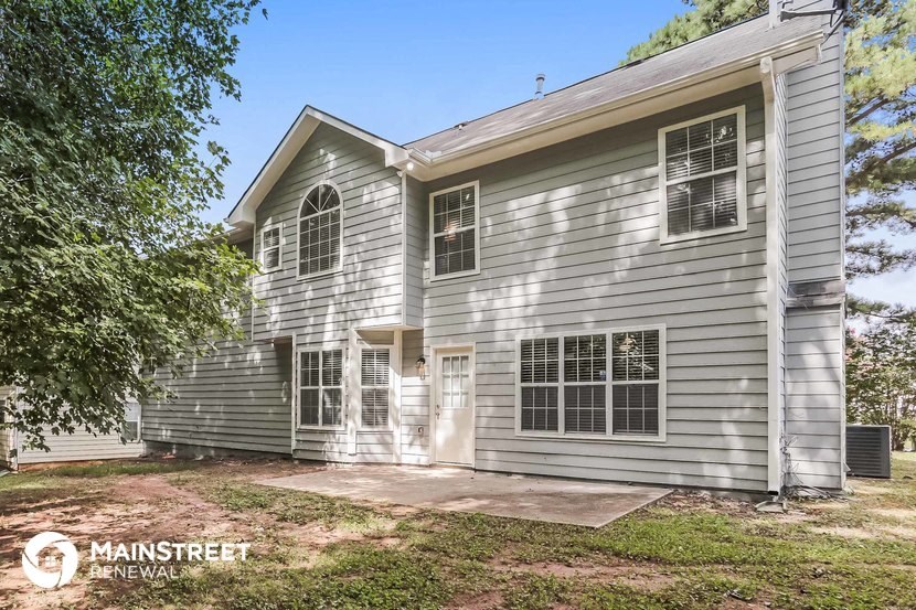 the front of a white house with a yard and trees