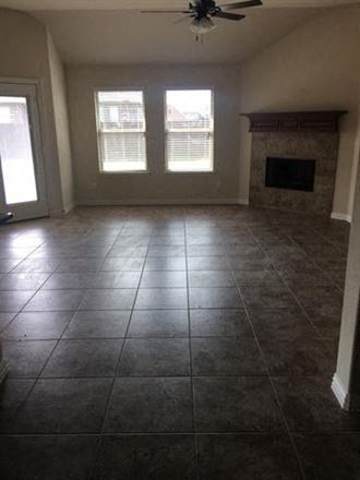 an empty living room with a fireplace and tiled floors