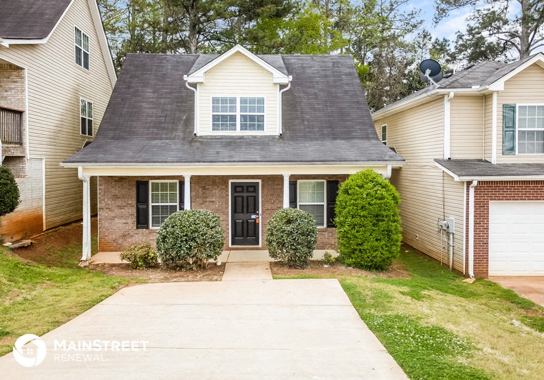 a small brick house with a sidewalk in front of it