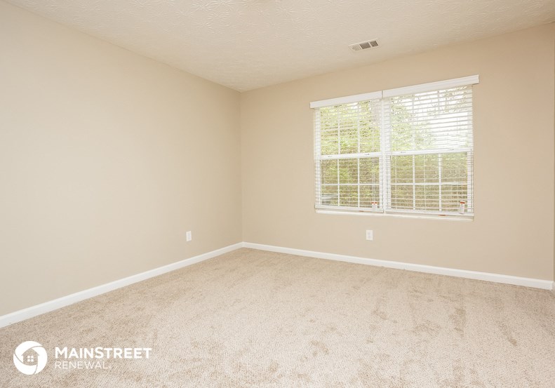 a bedroom with a large window and a carpeted floor
