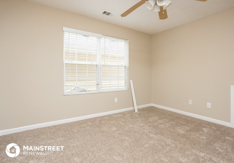 an empty room with a window and a ceiling fan