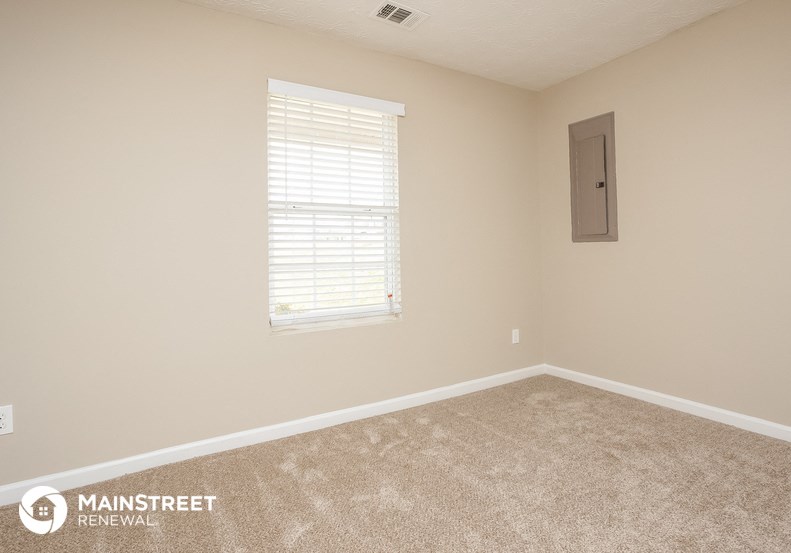 a carpeted room with a window and a door